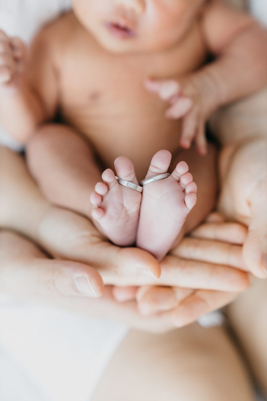 Newborn photography Kuala Lumpur baby feet with wedding rings on parents hands