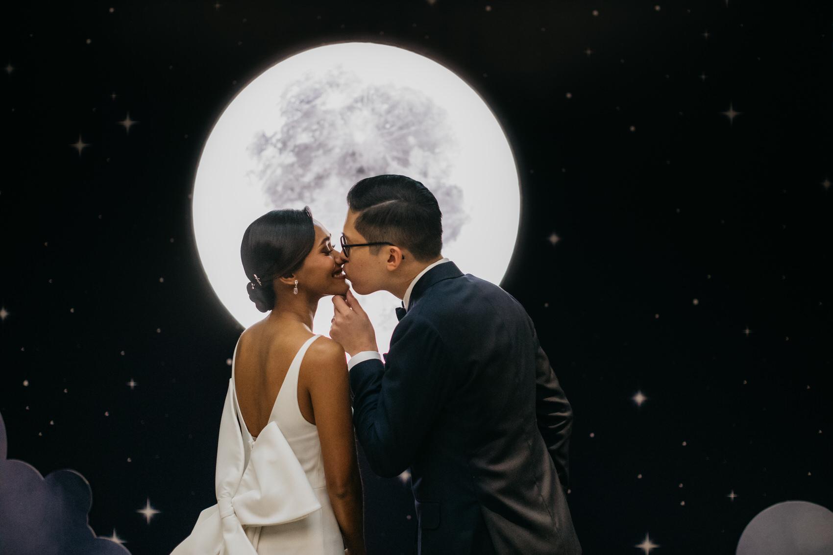 Couple Kissing Under the Moon. A dreamy and romantic, celestial moon-themed wedding reception at The Equatorial Hotel Kuala Lumpur. Liyana and Carlos's love shone bright like the moon at this magical venue. Cliff Choong Photography