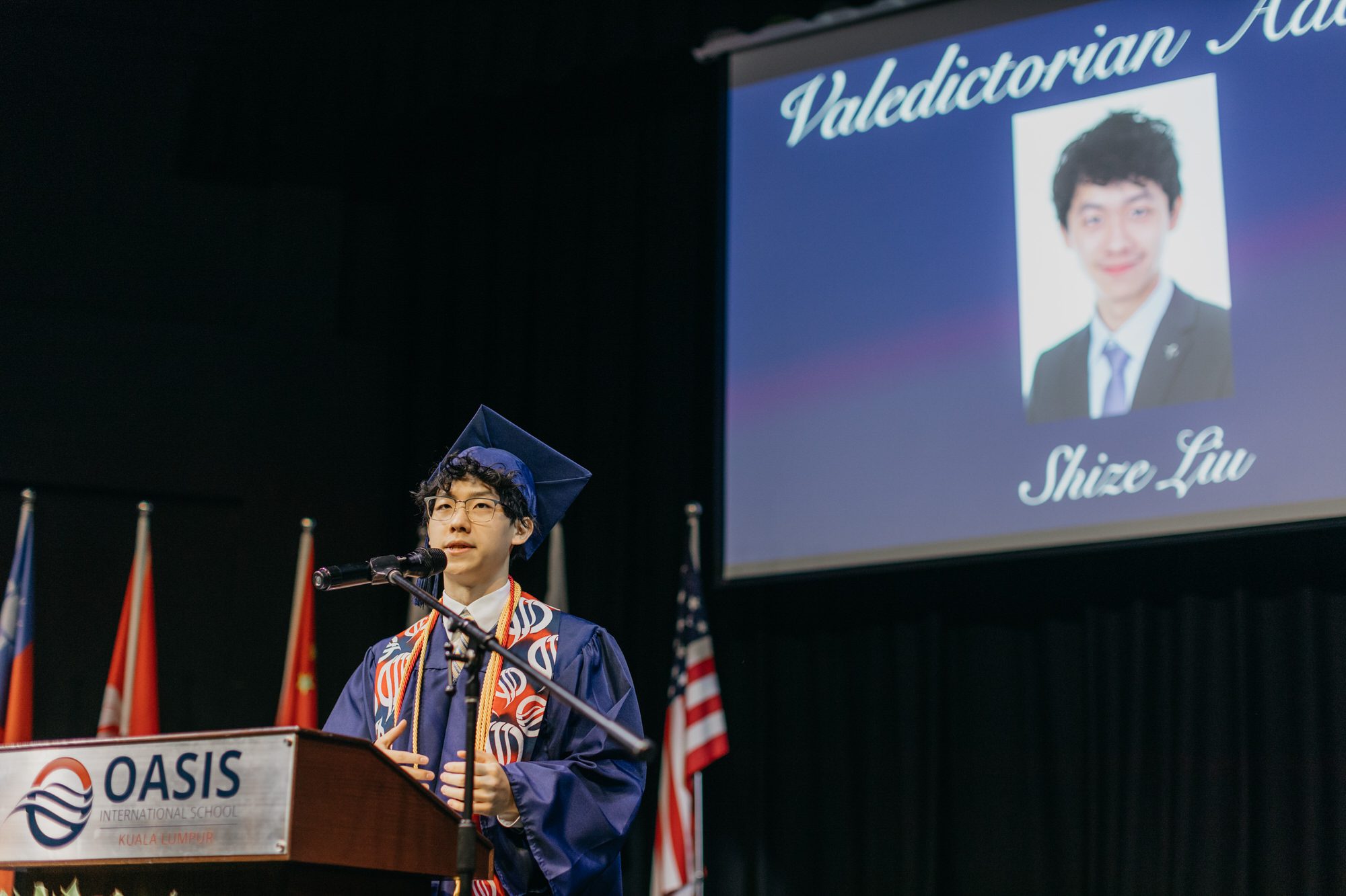 A confident student standing behind a podium, delivering a powerful valedictorian speech during the Oasis International School 2023 graduation ceremony.