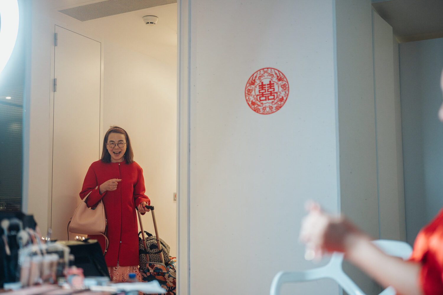 Mother of the bride watches as the bride gets her makeup done by the makeup artist at NHow Hotel in Rotterdam, adorned in traditional Chinese attire.