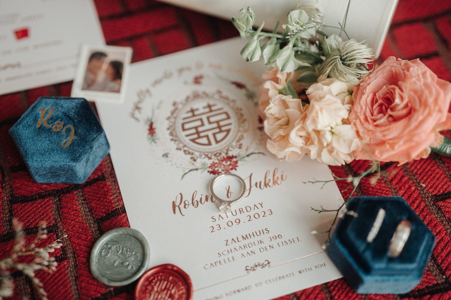Close-up wedding detail shot featuring the bride's engagement ring and wedding bands, alongside a beautifully arranged bouquet and invitation card, adding elegance to the preparations at NHow Hotel in Rotterdam. A Destination Wedding Photography in Rotterdam | Jukki & Robin