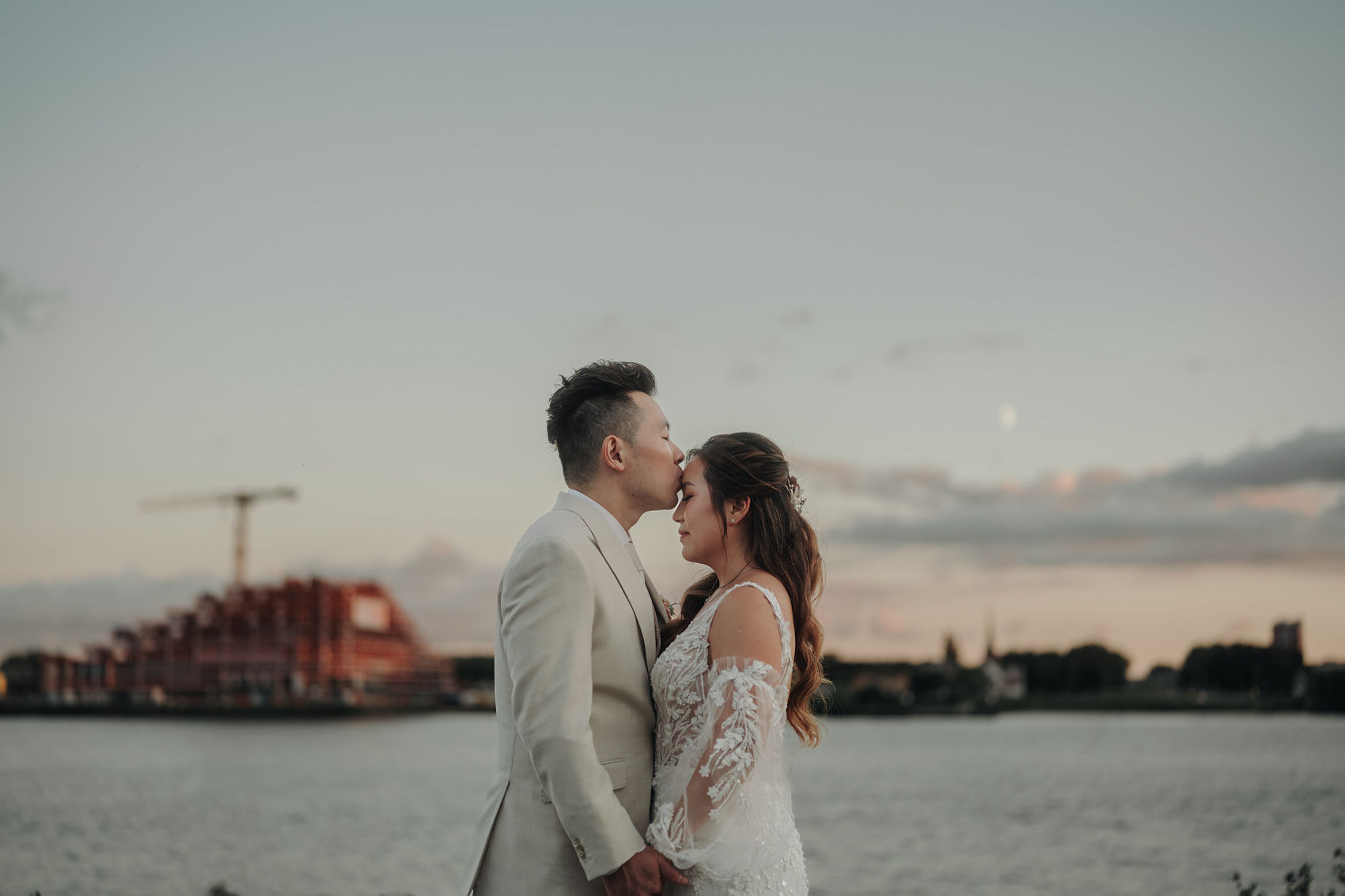 A Destination Wedding Photography in Rotterdam | Jukki & Robin Bride and groom posing for outdoor portraits by the riverside near Zalmhuis