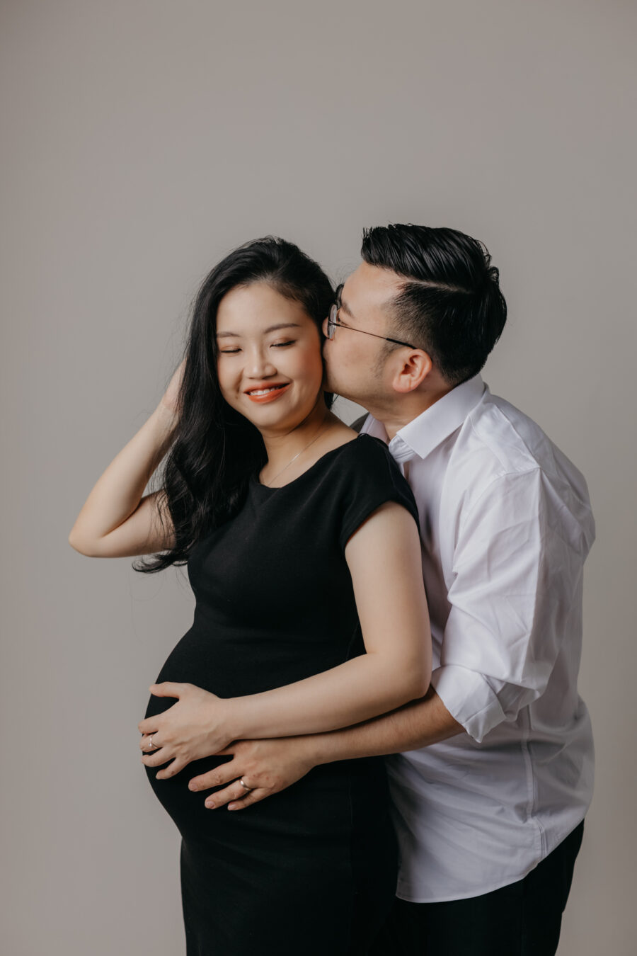 Expectant parents embracing during mini maternity session at Darkroom Project Studio
