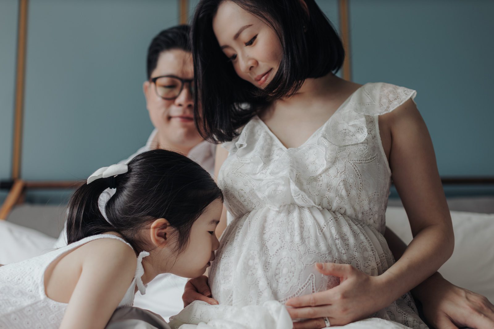 Little Girl Naomi Kissing Mother's Belly:Little Girl kissing her mother's baby bump while daddy lovingly looks on, capturing the family's excitement.