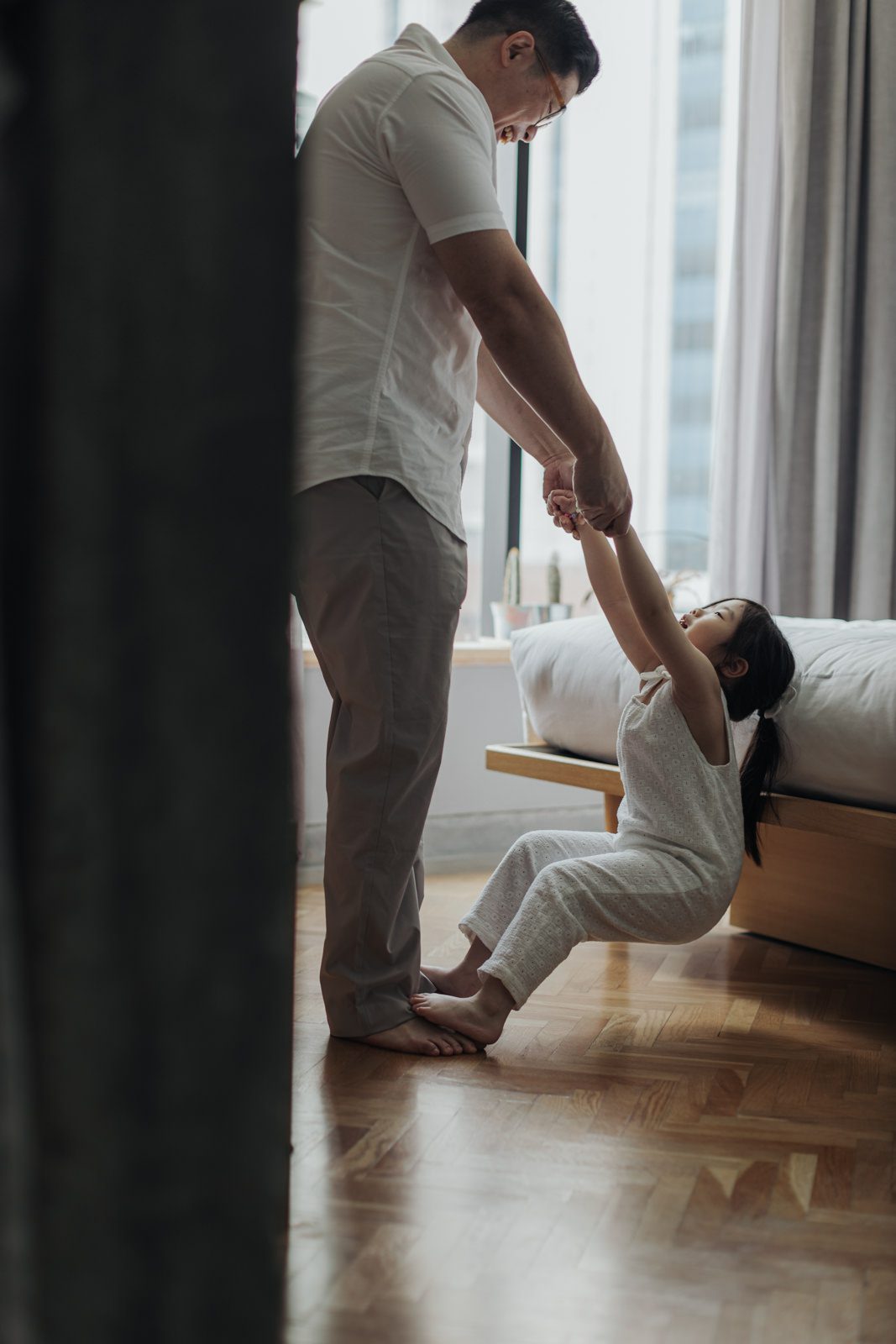 Father and Daughter Playtime: A father holding hands and playing with his young daughter in a bright, cozy room at KLoe Hotel.