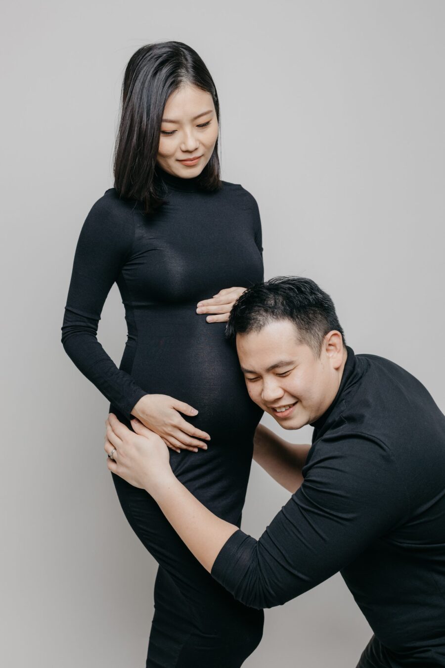 Father kneeling and hugging mother's baby bump during a maternity photo session.