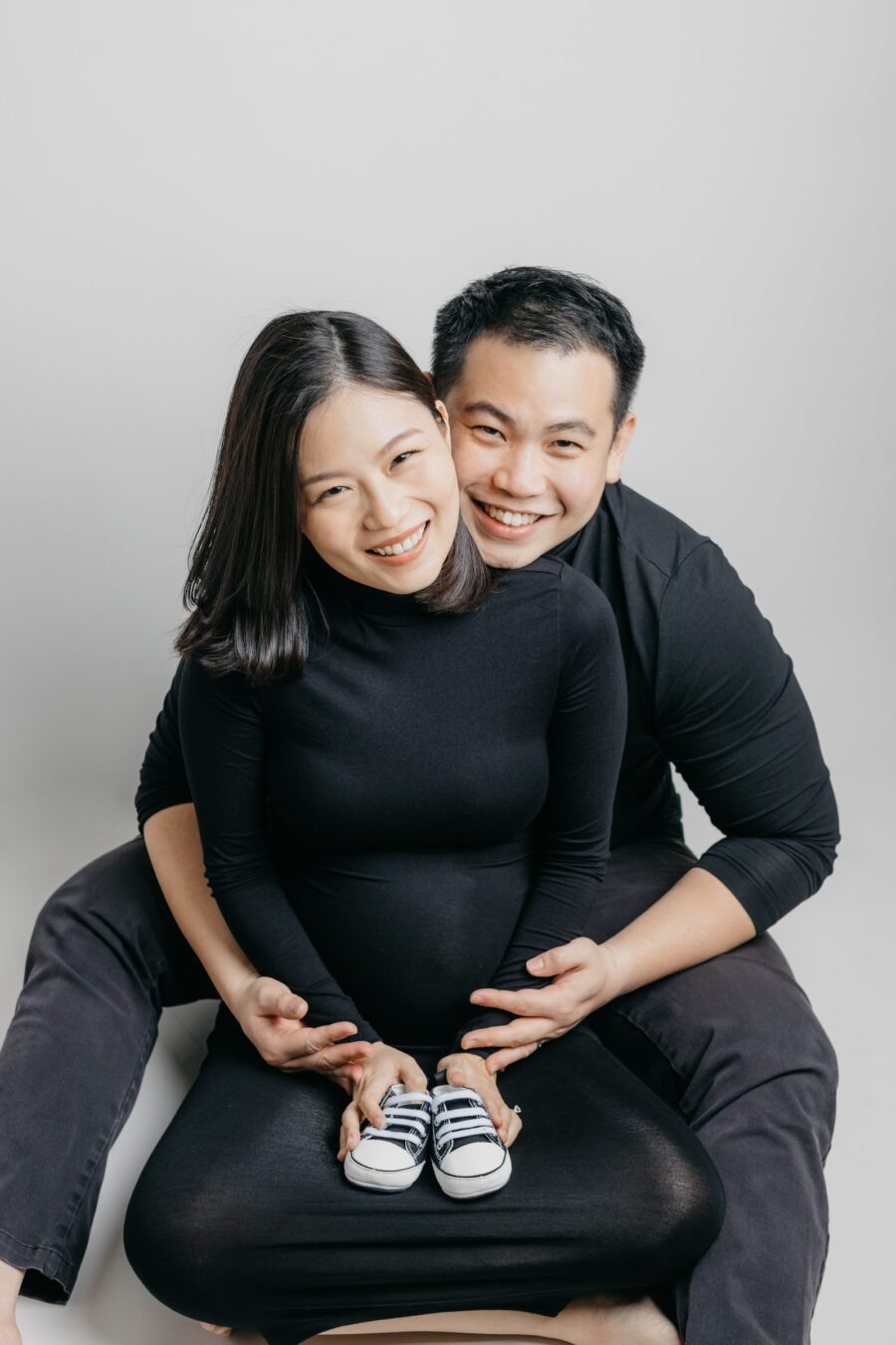 Father kneeling and hugging mother's baby bump during a maternity photo session.