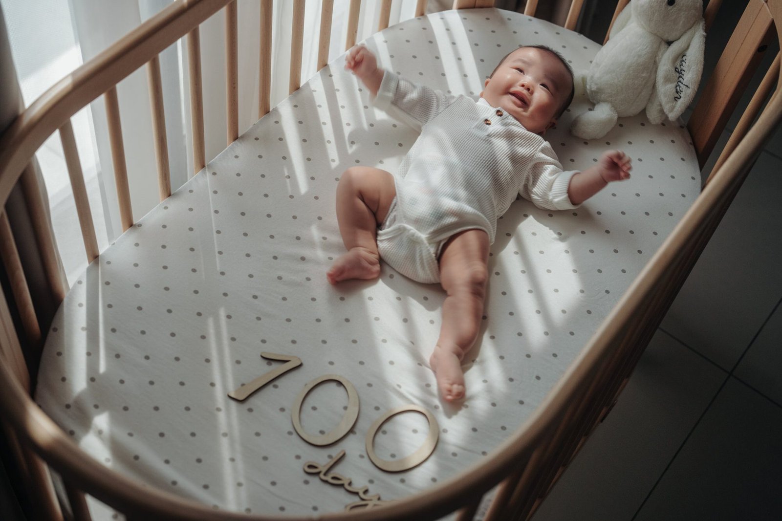 Smiling baby lying in crib during 100-day photoshoot