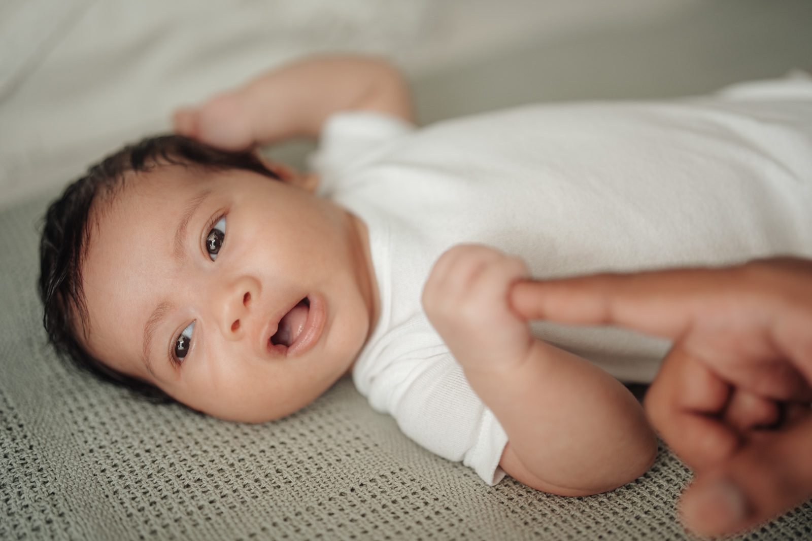 Side profile of Cleo gazing curiously, featuring a candid baby portrait in a naturally lit portrait at home moment. Cliff Choong Photography