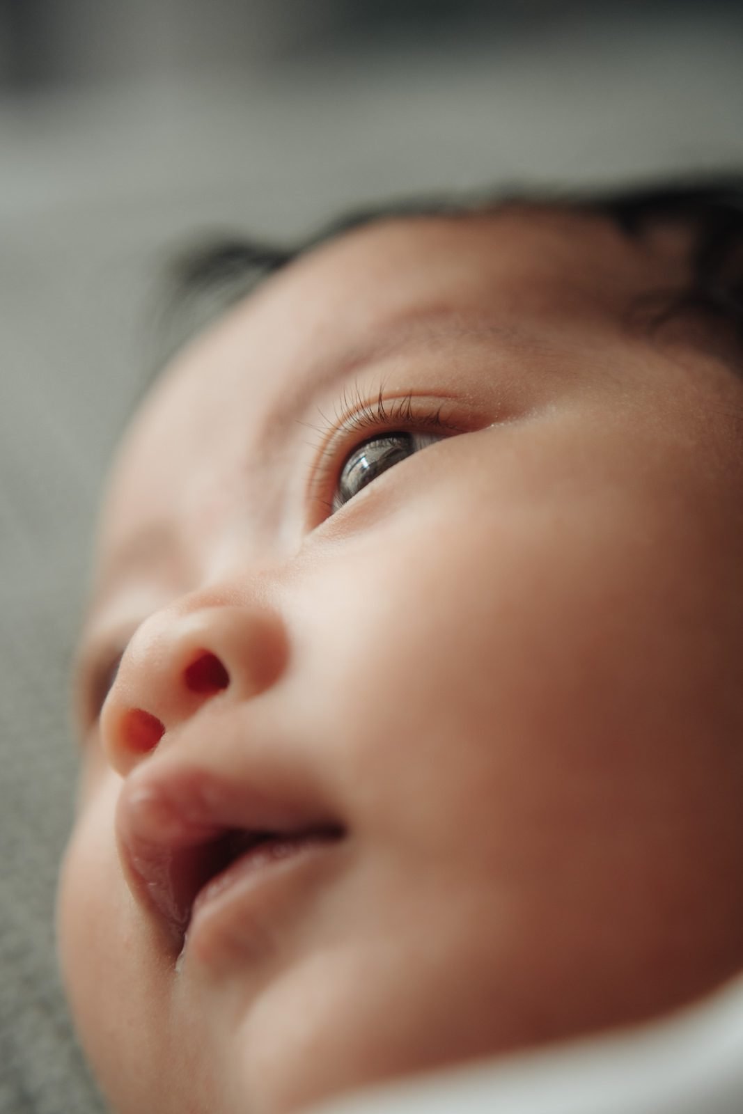 Side profile of Cleo gazing curiously, featuring a candid baby portrait in a naturally lit portrait at home moment. Cliff Choong Photography