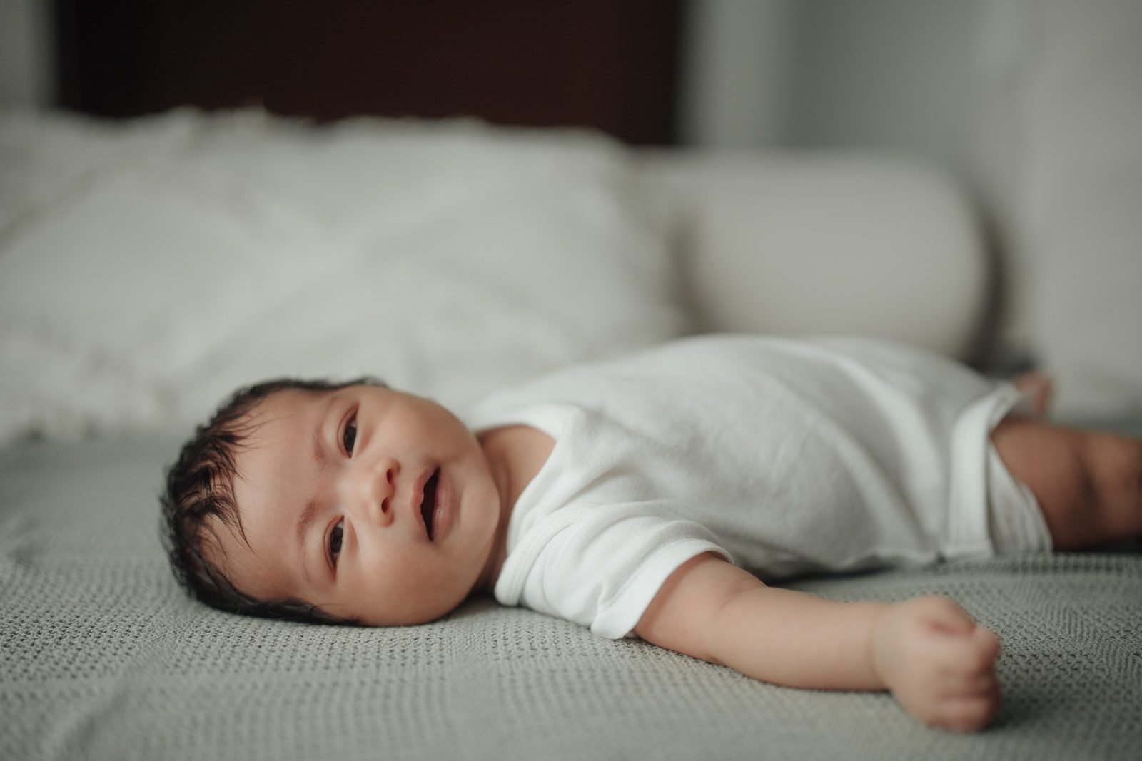 Side profile of Cleo gazing curiously, featuring a candid baby portrait in a naturally lit portrait at home moment. Cliff Choong Photography