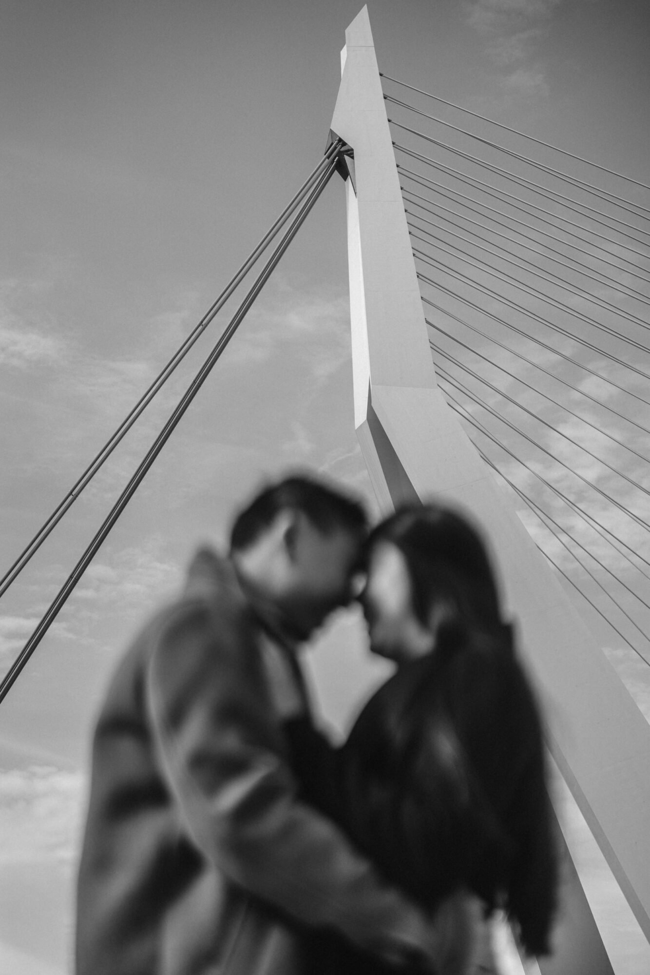 Couple standing beneath the modern Erasmus Bridge in Rotterdam