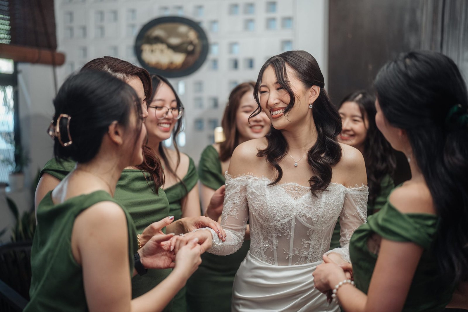 Bridesmaids laughing together with the bride in matching green dresses by Cliff Choong Photography