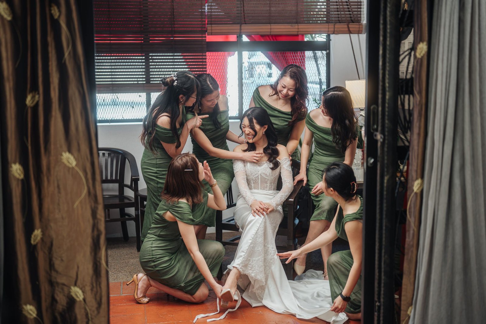 Bridesmaids laughing together with the bride in matching green dresses by Cliff Choong Photography